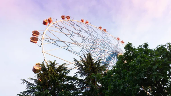 Roda gigante brilhantemente colorida contra o céu do pôr do sol. Lazarevskoye, Sochi, Rússia, Sobre a roda a inscrição Lazarevskoe — Fotografia de Stock