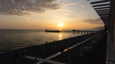 Portakal, günbatımını güneşin arka planında insan siluetleriyle doldurdu. Lazarevskoe, Soçi, Rusya