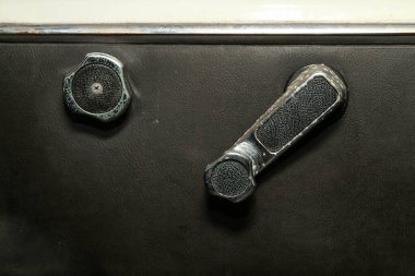 Eski klasik arabanın siyah yapay deri iç kısmının tadilata ihtiyacı var. Yırtık koltuk kılıfları ve paslı krom parçalarıyla.