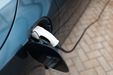 Şarj istasyonundaki prize takılı elektrikli arabanın üst görüntüsü.