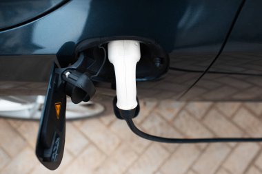 Elektrik kablosunun en üst görüntüsü bir elektrikli arabayı şarj ediyor.