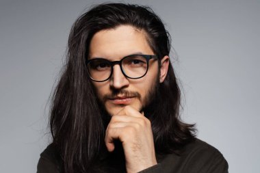 Genç yakışıklı bir adamın portresi. İfade eden yüzü ve uzun saçları var. Gözlük takıyor..