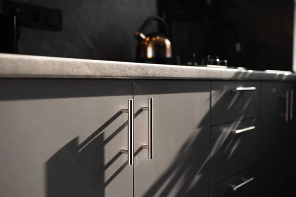 Close-up of handles of kitchen furniture of grey colour.