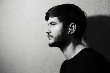 Siyah ve beyaz arka planda kulaklıkları olan genç bir adamın portresi..