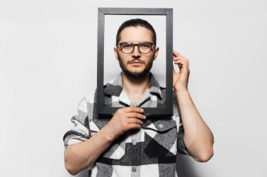 Ekose gömlekli, siyah ahşap çerçeveli genç adamın stüdyo portresi..