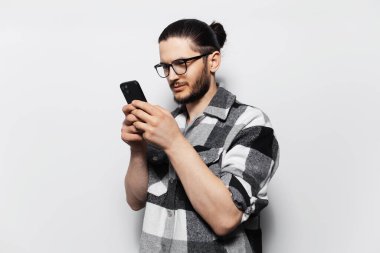 Ekose gömlekli, elinde akıllı telefon tutan çekici bir gencin stüdyo fotoğrafı..