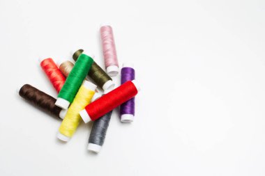 Beyaz arkaplanda renkli iplik makaralarının üst görüntüsü.