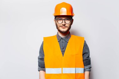 Genç inşaatçının fotoğrafı. Turuncu şapka ve gözlük takıyor..