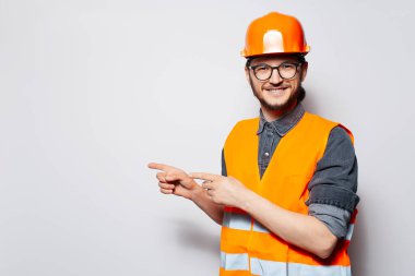 Genç ve mutlu inşaat işçisinin portresi beyaza boşluğu işaret ediyor..