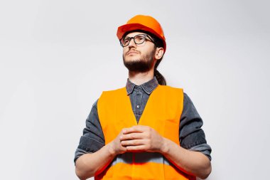 Beyaz üzerine kendinden emin genç inşaat işçisinin stüdyo portresi. Yukarı bakıyorum..