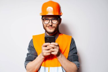 Beyaz arka planda akıllı telefon kullanan kendine güvenen bir mühendisin portresi.