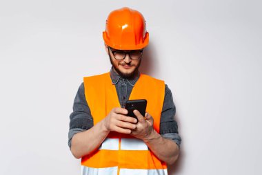 Akıllı telefonda, beyaz arkaplanda yazı yazan inşaat mühendisinin portresi.