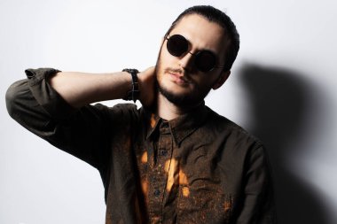 İnsan portresi, el boynun arkasında, beyaz güneş gözlüğü takıyor..