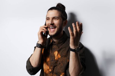 Genç mutluluk adamı beyaz stüdyonun arkasında akıllı telefondan konuşuyor..