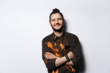 Beyaz arka planda, saçı topuzlu mutlu bir adamın stüdyo portresi..