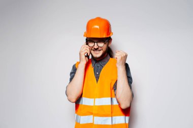 İşte bu! Akıllı telefondan konuşan mutlu mühendisin portresi, beyaz arka planda.