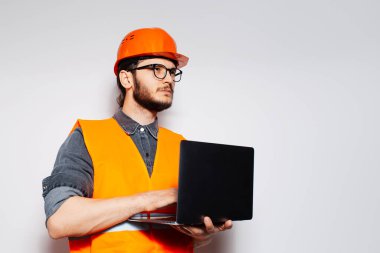 Beyaz arka planda dizüstü bilgisayarı olan genç mühendisin portresi.