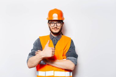 Beyaz arkaplanda baş parmak gösteren genç mühendisin portresi.