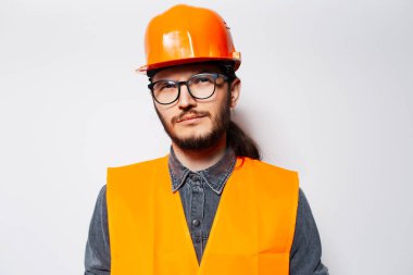 Gözlük ve turuncu inşaat ekipmanı takan genç bir mühendis..
