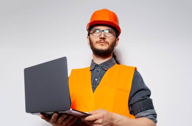 Turuncu inşaat ekipmanlarında dizüstü bilgisayar kullanan mühendisin portresi.