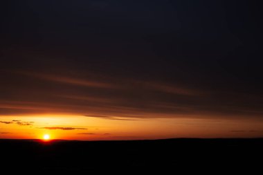 Koyu bulutlu, renkli günbatımının doğal manzarası.