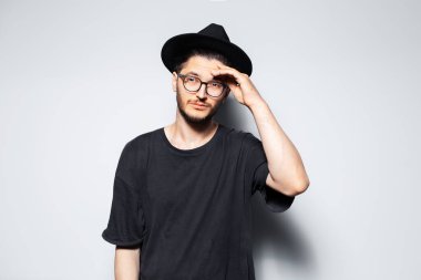 Siyah şapkalı ve gözlüklü yakışıklı bir adamın stüdyo portresi..
