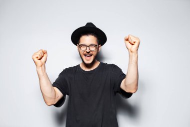 Siyah fötr şapkalı, neşeli ve başarılı genç adamın stüdyo portresi..