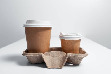 Karton tutacağa yakın çekim, beyaz masa üzerinde kahve fincanları..