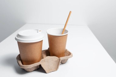 Kağıt bardaklı, beyaz masalı mukavva tutucu. Grinin arkaplanı.