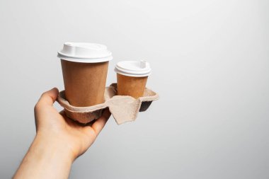 Kahve siparişi için elinde iki kağıt bardak olan bir erkek..