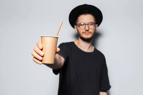 Close-up of paper cup with bamboo straw in male hand on white background.