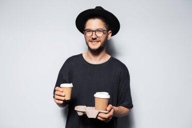 Elinde karton tutacağıyla beyaz kahve taşıyan genç adamın portresi..