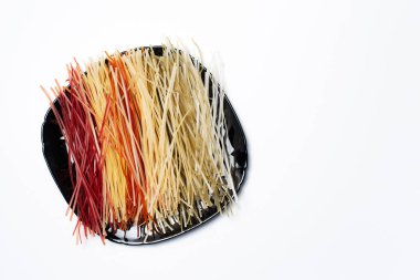 Tabakta farklı renkler olan ham makarnanın üst görünümü, kopyalama alanı olan beyaz üzerine.