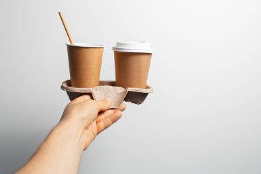 Erkek, elinde karton tutacağı, yanında da iki fincan kahve..