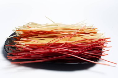 Siyah tabakta farklı renkte, beyaz arkaplanda, ham makarnanın yakın plan görüntüsü.