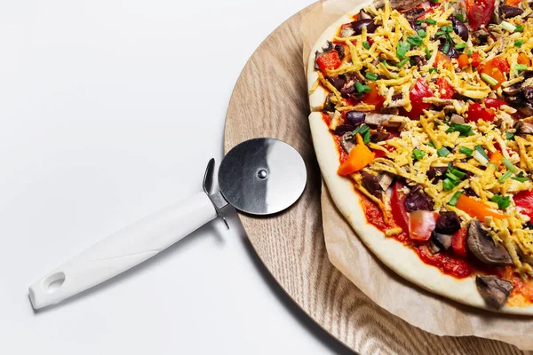 Close-up of homemade vegan pizza and knife on wooden table and white background.