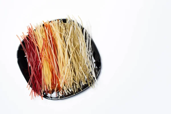 Tabakta farklı renkler olan ham makarnanın üst görünümü, kopyalama alanı olan beyaz üzerine.