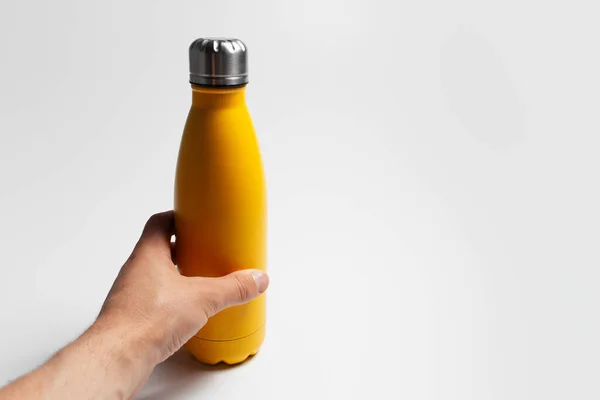 白に黄色の男性の手を保持鋼エコ再利用可能な水ボトルのクローズアップ — ストック写真
