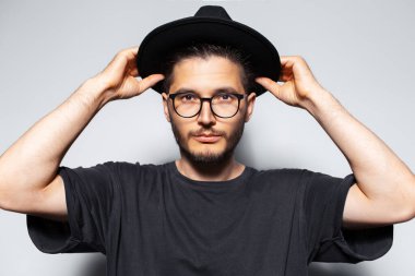 Beyaz stüdyo arka planında kafasından şapka tutan yakışıklı adamın portresi..