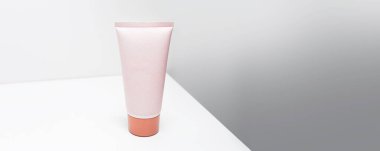 Gri arkaplanda pembe renk kozmetik tüp görüntüsü panoramik afiş.