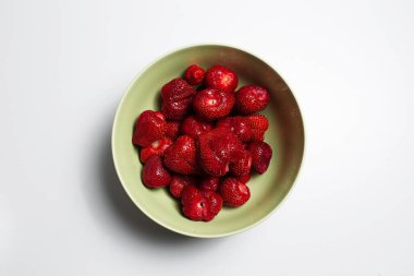 Beyaz arka planda çilekli yeşil kasenin yakın plan görüntüsü..