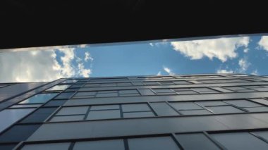 Güneşli bir günde, iki modern bina arasındaki mavi gökyüzü manzarası.
