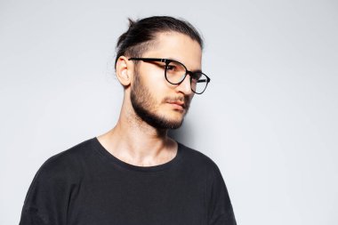 Beyaz arka planda gözlük takan genç adamın yan portresi..