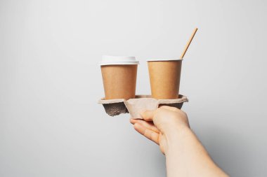 Erkek, elinde karton tutacağı, yanında da iki fincan kahve..