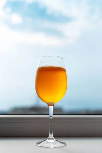 Close-up of glass of beer on background of blue cloudy sky.