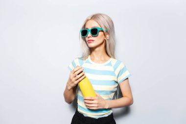 Beyaz arka planda sarı termosu olan güzel bir kızın portresi..