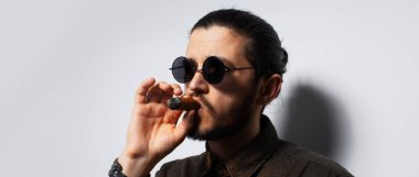 Beyaz arka planda purosu olan genç bir adamın stüdyo portresi. Panoramik pankart.