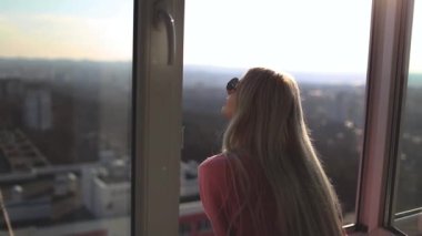Kızın arka manzarası daire penceresini açıyor, güzel manzaranın tadını çıkarıyor..