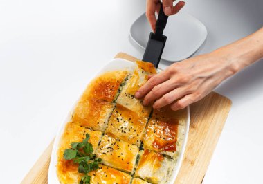 Kadın eli, Yunan turtası spanakopitasından bir parça alıyor. Ev yapımı vejetaryen yemeği.