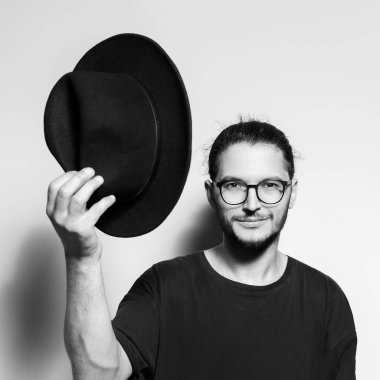 Yakışıklı bir adamın siyah beyaz portresi şapkasını çıkarır..